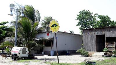 Carlos Álvarez muestra el panel solar que compró para tener luz en su casa y extraer agua de un pozo en Miami. En Barra Vieja, una aldea vecina, solamente en esta pulpería hay energía. Aquí los garífunas pagan L10.00 por cargar los celulares. F. MUÑOZ