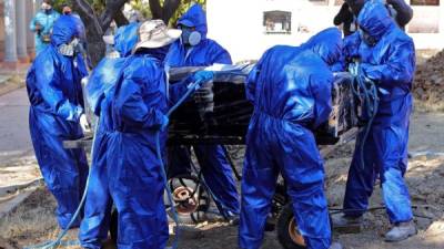Los empleados sanitarios trasladan los cuerpos de las casas al cementerio de Cochabamba, colapsado por las muertes de covid 19./AFP.