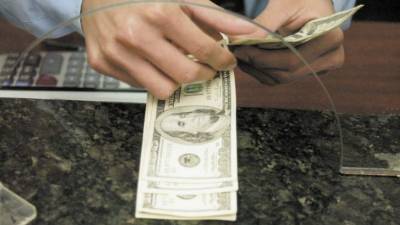 Un cajero cuenta billetes de cien dólares.