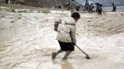 Fotografía de archivo fechada el 30 de abril de 2012 que muestra a varias personas intentando limpiar de barro una carretera tras una lluvia torrencial seguida de un corrimiento de tierra en la provincia de Badakhshan, en Afganistán. EFE