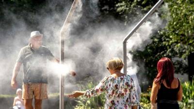 Varios ciudadanos franceses tratan de refrescarse con rociadores de agua en la ciudadde Lille, en el norte de Francia.