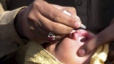 Un trabajador de sanidad da la vacuna de la polio a una joven en Chamán (Pakistán). EFE/Archivo