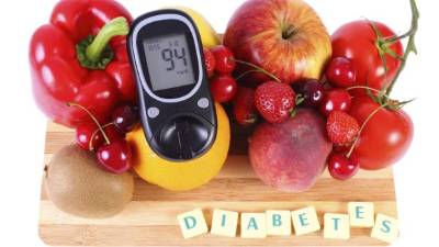 Glucometer with fresh ripe fruits and vegetables on wooden cutting board, concept of diabetes, healthy food, nutrition and strengthening immunity