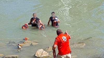 Un agente mexicano lanza una cuerda para rescatar a tres migrantes que estaban a punto de ahogarse en el río Bravo.