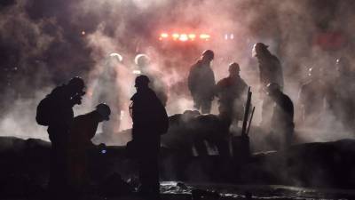 Los bomberos apagan el fuego ardiente sobre los cuerpos de las víctimas quemadas. Foto: AFP