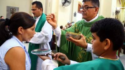 El padre José Canales entrega el cuerpo de Cristo a una feligresa. Foto: Franklin Muñoz