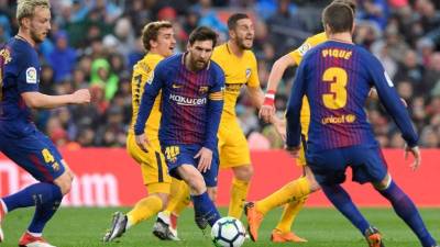 Barcelona's Argentinian forward Lionel Messi (C) eyes the ball during the Spanish league football match FC Barcelona against Club Atletico de Madrid at the Camp Nou stadium in Barcelona on March 04, 2018. / AFP PHOTO / LLUIS GENE