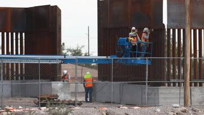 Trabajadores refuerzan el muro fronterizo.