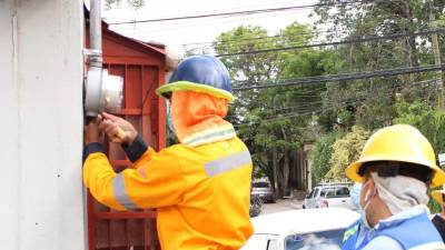 Trabajadores de la Enee revisan un contador de energía.