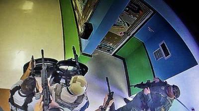 Imágenes de cámaras de seguridad muestran a los oficiales armados y con escudos balísticos esperando en las afueras del salón de clase donde ocurrió la masacre.
