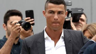 Portuguese footballer Cristiano Ronaldo surrounded by photographs looks on as he greets supporters outside the Juventus medical center at the Alliance stadium in Turin on July 16, 2018.Cristiano Ronaldo arrived in Turin ahead of his official unveiling as Juventus' superstar summer signing on July 17. / AFP PHOTO / Isabella Bonotto