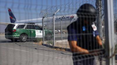 A police officer guards a gate at the Arturo Merino Benitez International Airport in Santiago on March 8, 2023, after the failed robbery of more than 32 million US dollars from an armoured van which had just picked the money from a Latam Airline plane arriving from Miami. - An officer of the General Direction of Civil Aviation and one of the attackers were killed in a shootout. (Photo by Karin POZO / AFP)