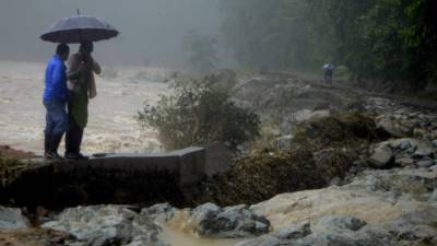 La destrucción parcial de la carretera que comunica a las comunidades de la cuenca del Cangrejal ha obligado a sus habitantes a tener que movilizarse a pie en medio de balseras y rocas dejadas por las crecidas del río.