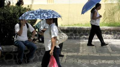Muchos se protegen con sombrillas de los fuertes rayos del sol. Foto: Wendell Escoto.