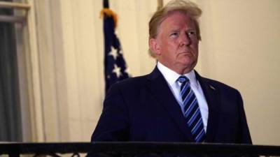 TOPSHOT - US President Donald Trump looks out from the Truman Balcony upon his return to the White House from Walter Reed Medical Center, where he underwent treatment for Covid-19, in Washington, DC, on October 5, 2020. (Photo by NICHOLAS KAMM / AFP)