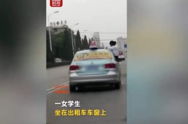 Captura del vídeo donde muestra a la joven sobre el capo del carro haciendo tareas.