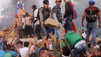 Personas intentan sacar parte de la ayuda humanitaria que se encuentra un camión que fue quemado, este sábado, en Ureña (Venezuela). EFE