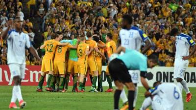Australia's team celebrates their victory, as Honduras' players react, after their World Cup 2018 qualifying football match in Sydney on November 15, 2017. / AFP PHOTO / Saeed KHAN / -- IMAGE RESTRICTED TO EDITORIAL USE - STRICTLY NO COMMERCIAL USE --