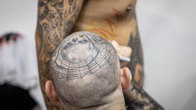 Un tatuador trabaja en el costado de una persona, durante una convención de tatuadores este sábado en Ciudad de Guatemala.