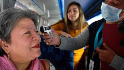 A Health Ministry doctor takes the temperature to a passenger on arrival at the bus terminal, as a preventive measure in the face of the global COVID-19 coronavirus pandemic, in Bogota on March 13, 2020. - Colombia declared on March 12, 2020 a 'Health Emergency' due to the new coronavirus pandemic, a figure that allows it to take exceptional measures such as prohibiting the disembarkation of cruise ships and the holding of public events with more than 500 attendees. (Photo by Raul ARBOLEDA / AFP)