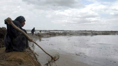Una mujer busca sus pertenencias en los campos inundados en la localidad de Sheberghan, Afganistán.