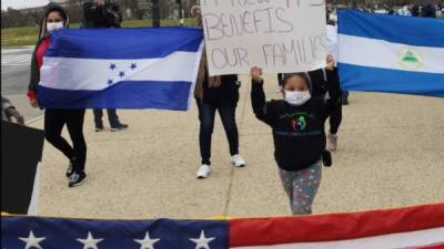 Decenas de hondureños sostienen pancartas y banderas estadounidenses mientras marchan dirección a la Casa Blanca, en Washington . EFE