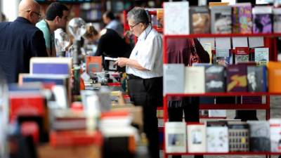 Un hombre observa un libro en una feria de libros en Costa Rica.