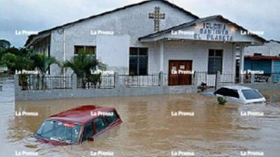 Colonia Planeta, La Lima. Durante. Decenas de vehículos permanecieron sumergidos en las calles tras el desbodarmiento del río Chamelecón Después. Con las últimas lluvias, en esta calle (frente a la Iglesia Bautista El Planeta) se han formado lagunas.