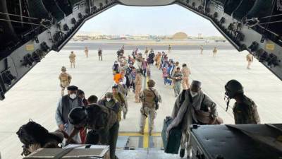 In this handout image released on August 18, 2021 by La Moncloa, Spaniards who remain in Afghanistan as well as Afghans and their families who worked at the Spanish side, queue to board the first Spanish Air Force Airbus A400M headed to Dubai at the Kabul airport. - Afghans and foreigners have been desperately trying to flee the country since the Taliban's comeback, with the United States and other nations stepping up evacuation airlifts from Kabul. (Photo by Handout / LA MONCLOA / AFP) / RESTRICTED TO EDITORIAL USE - MANDATORY CREDIT 'AFP PHOTO / LA MONCLOA' - NO MARKETING - NO ADVERTISING CAMPAIGNS - DISTRIBUTED AS A SERVICE TO CLIENTS