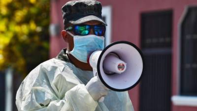 A sergeant asks resident of La Rosa colony through a megaphone to stay home as soldiers deliver food aid before the start of a curfew here, and at Flor del Campo colony, as part of the fight against the novel coronavirus, COVID-19, in Tegucigalpa on April 28, 2020. - More than 211,185 people have died worldwide since the epidemic surfaced in China in December, according to an AFP tally at 1100 GMT on Tuesday based on official sources. (Photo by Orlando SIERRA / AFP)