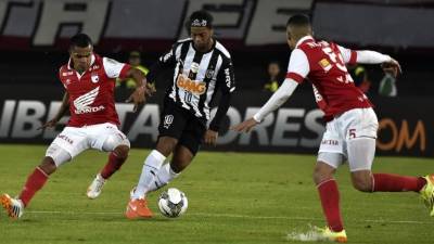 David Arturo Ferreira (izq) y Yulian José Patiño de Santa Fe marcan a Ronaldinho.