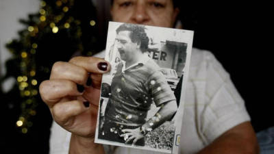 Cecilia Monsalve, residente del barrio Pablo Escobar, muestra una fotografía con la imagen de este capo de la droga hoy, lunes 2 de diciembre de 2013, en Medellín (Colombia). Pablo Escobar, al que se atribuyen más de 5.000 asesinatos y cientos de atentados terroristas, murió en Medellín el 2 de diciembre de 1993, abatido por los disparos de la policía en una persecución, digna de una película, por los tejados de la ciudad. El mayor traficante de la historia quien murió abatido hace hoy veinte años, dejó como legado en su país un modelo del narcotráfico que si bien ha ido mutando su estructura con el tiempo se mantiene todavía vigente. EFE