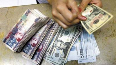 Una persona cuenta dólares, lempiras y euros.