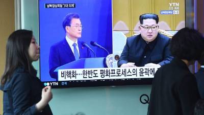 Una mujer pasa frente a una pantalla de noticias que muestra imágenes de archivo del presidente surcoreano Moon Jae-in y el líder norcoreano Kim Jong Un.
