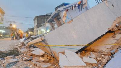 La gente se reúne al lado de una casa derrumbada en Guayaquil.