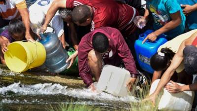 Cientos de personas sacaron agua del río Guaire, el más contaminado de Venezuela, para bañarse y cocinar tras la escasez generada por la falta de energía en los últimos días./AFP.