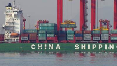 Esta foto tomada el 6 de diciembre de 2015 muestra contenedores que se descargan de un barco en un puerto de Rizhao, provincia de Shandong, este de China. AFP
