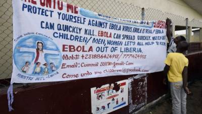 En Liberia, voluntarios extienden una pancarta explicando medidas de prevención contra el letal virus.