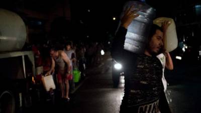 La gente hace cola para obtener agua potable distribuida en un camión cisterna. AFP