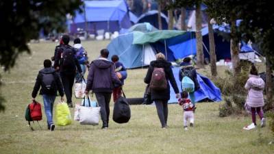 Personas abandonan el campamento de migrantes al norte de Francia. AFP