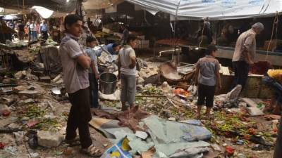 Varias personas caminan sobre los escombros en un mercado de la ciudad siria de Aleppo.