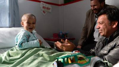 In this photograph taken on April 6, 2014, Abuzar Ahmad, the youngest son of slain Afghan AFP reporter Sardar Ahmad, plays during a visit by his uncle Bashir Mirzad (R) and AFP Bureau Chief for Pakistan-Afghanistan Emmanuel Duparcq (C) at a local hospital in Kabul. The orphaned Afghan child whose family was gunned down in a luxury Kabul hotel may soon leave hospital after recovering rapidly from bullet wounds to his skull, chest and thigh, doctors said. Abuzar Ahmad, aged two years and 11 months, suffered fragment wounds in the shooting on March 20 that killed his father, senior AFP reporter Sardar Ahmad, mother Homaira, sister Nilofar, 6, and brother Omar, 5. Abuzar's relatives hope that he will start a new life with many of his cousins who live in Toronto, Canada. 'He could be discharged within a week or 10 days if things continue to go well,' Luca Radaelli, medical coordinator at the Italian-run Emergency Hospital in Kabul, told AFP. AFP PHOTO/Wakil Kohsar