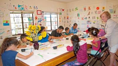 Un grupo de niños migrantes y algunos padres participan en una clase de arte del albergue para familias migrantes en el antiguo Monasterio Benedictino en la ciudad de Tucson. EFE