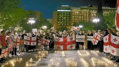 Georgians living in Greece, displaying Georgian flags, chant slogans as they stand around a display of candles reading 'Stop Russia!', during a demonstration in Athens' central Syntagma Square, Monday, Aug. 11, 2008. Russian planes continued air strikes in Georgia Monday in response to a military offensive against separatists in Georgia's South Ossetia region. (AP Photo/Petros Giannakouris)