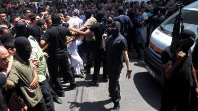 Armed Palestinian masked militants push back a crowd of worshippers outside a mosque in Gaza City after Friday prayers on August 22, 2014, before executing 18 men for allegedly helping Israel in its six-week assault on the Palestinian enclave. Six of them were grabbed from among hundreds of worshippers leaving the city's largest mosque, by men in the uniform of Hamas's military wing, the Ezzedine al-Qassam Brigades, witnesses told AFP. AFP PHOTO / STR