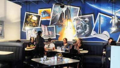 Fotografía que muestra murales decorados con motivos espaciales y comensales siendo atendidos en el interior del restaurante Space Age Lodge, localizado en Gela Bend, Arizona. EFE