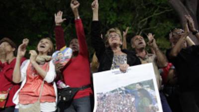 People, some of them holding an image of Venezuela's President Hugo Chavez, gather to pray for him at a church in Caracas, Venezuela, Monday, Dec. 31, 2012. Venezuela's President Hugo Chavez is confronting 'new complications' due to a respiratory infection nearly three weeks after undergoing cancer surgery, his Vice President Nicolas Maduro said Sunday evening in Cuba as he visited the ailing leader for the first time since his operation. (AP Photo/Ariana Cubillos)