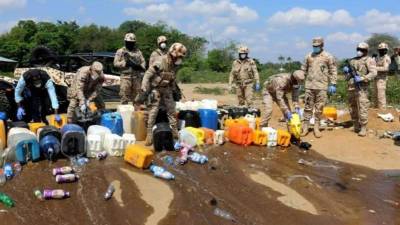 Fotografía cedida por el Cuerpo Especializado de la Seguridad Fronteriza de República Dominicana (Cesfront) que muestra a varios miembros de la institución destruyendo varios galones de clerén o triculí incautados en Dajabón (R. Dominicana). EFE/CESFRONT
