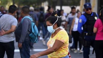 Una mujer camina por el centro histórico de San Salvador mientras usa una máscara facial como precaución. Foto: AFP