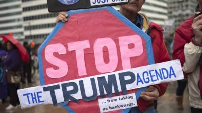 Un hombre sostiene una pancarta en la que se puede leer 'Parad a la agenda Trump' en la plaza Thomas Paine delante del hotel Loews Philadelphia en Filadelfia, Estados Unidos.